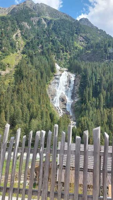 ein Holzzaun vor einem Wasserfall und einem Berg