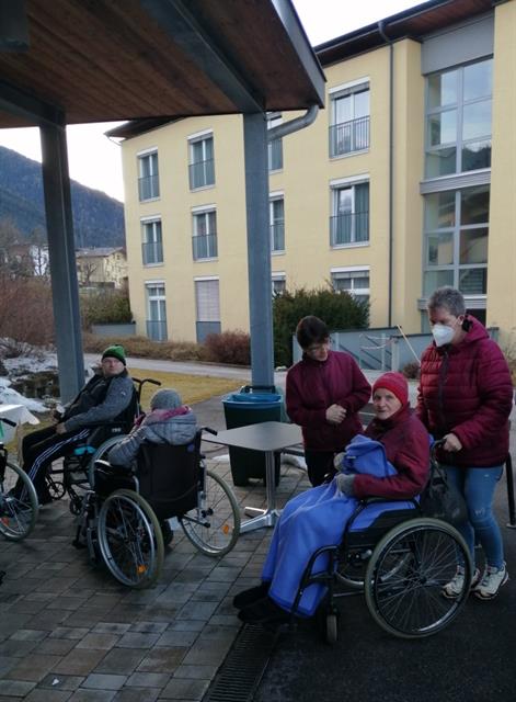 Eine Gruppe von Menschen, die in Rollstühlen vor einem Gebäude sitzen