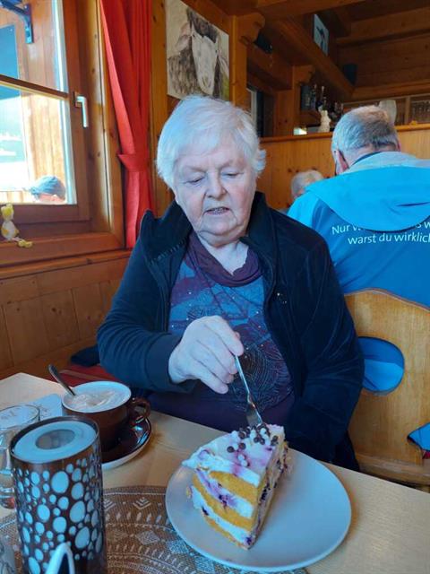 Eine alte Frau, die einen Kuchen anschneidet