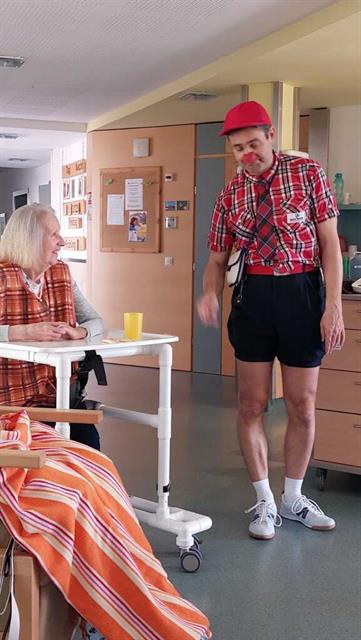 ein mann mit rotem hut und shorts steht neben einer frau in einem krankenhausbett