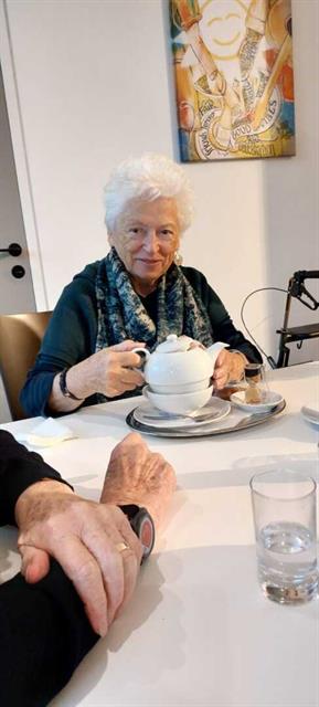 eine ältere Frau sitzt an einem Tisch